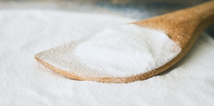 pile of white powder on table. wooden spoon in the powder.
