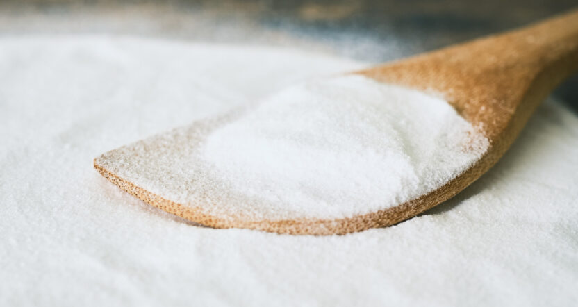 pile of white powder on table. wooden spoon in the powder.